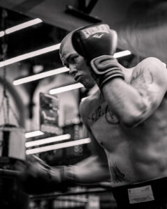 Boxer training on a heavy bag in a black and white gym setting