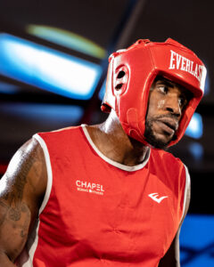 Boxer wearing red headgear inside the boxing ring before a bout