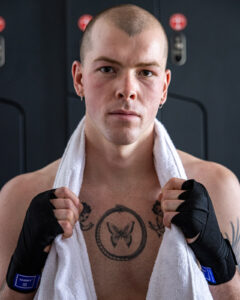 Boxer staring at camera with wrapped hands and towel around neck