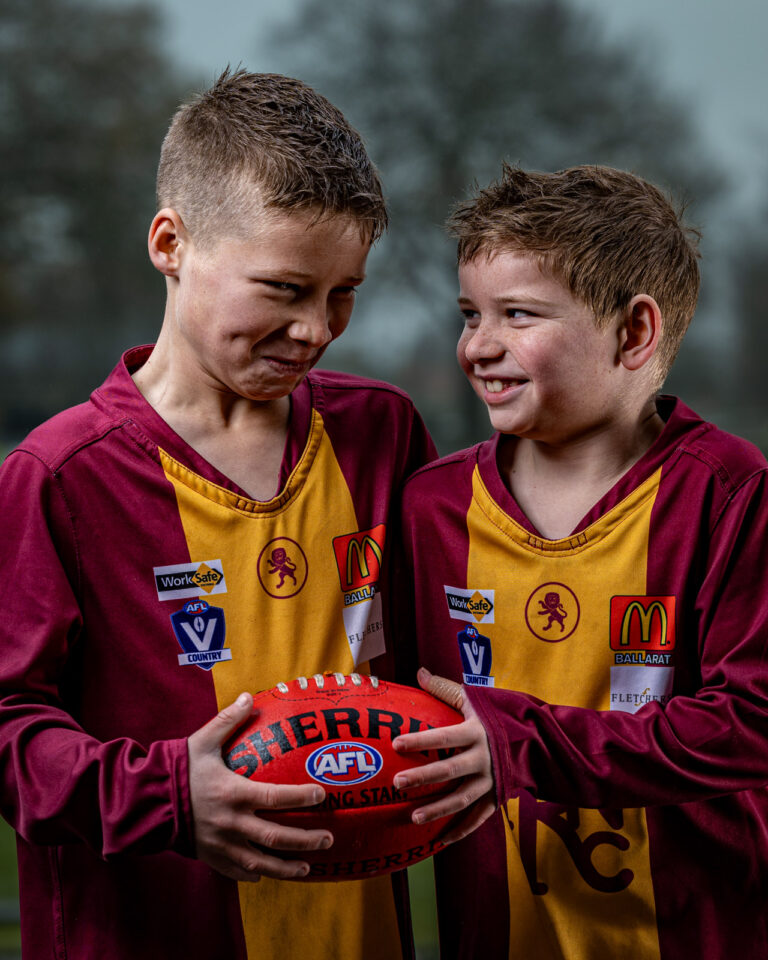 Two young boys smiling while holding a football together