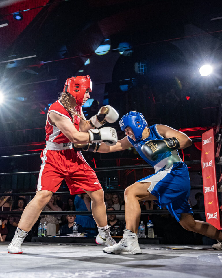 Female boxer landing a body shot on her opponent during a bout