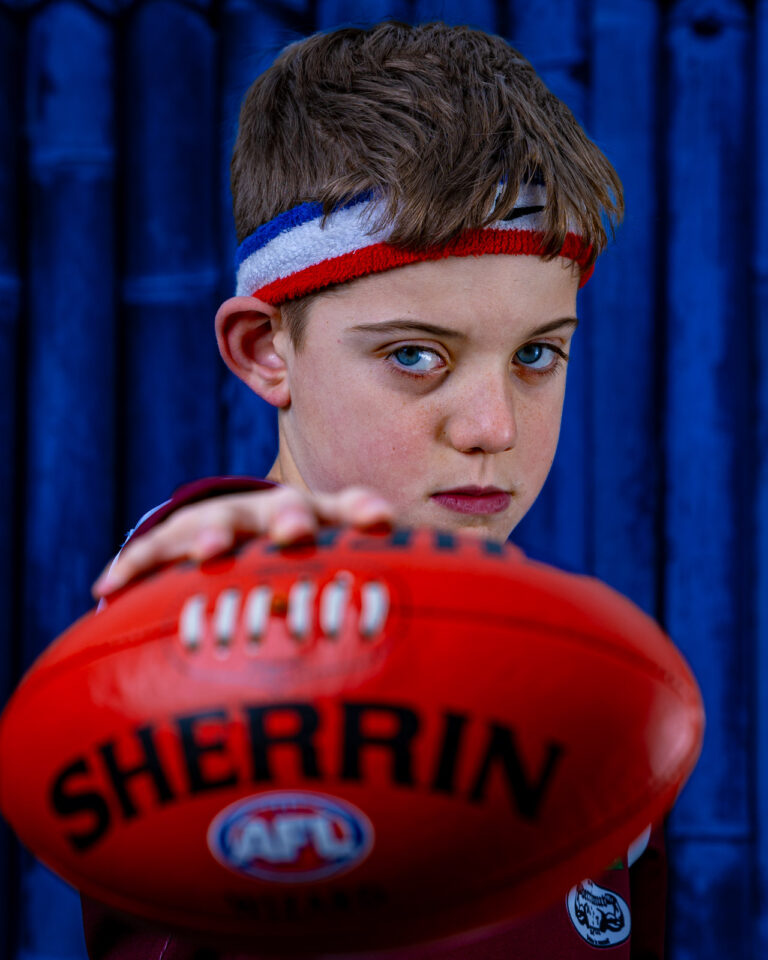 Young boy holding a football with a focused expression