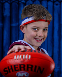 Young boy smiling while holding a football