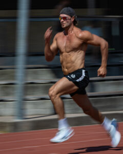 An athlete sprints down a running track at full speed, captured with motion blur to emphasise movement and intensity.