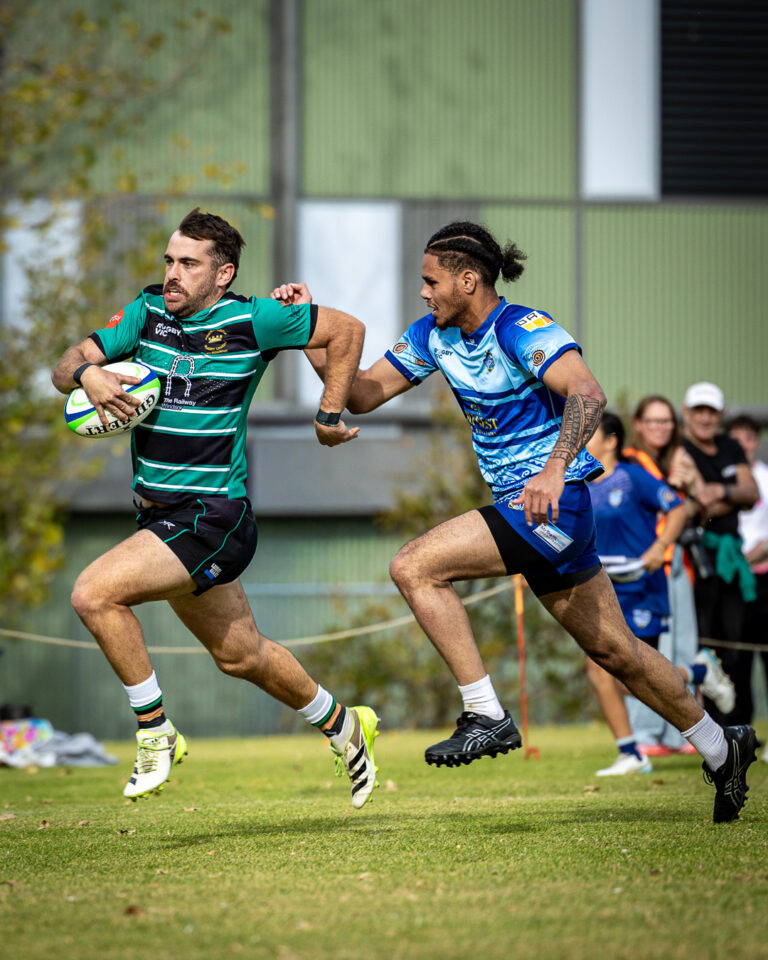 A Power House Rugby player sprints downfield while being chased by a defender during a rugby union match.