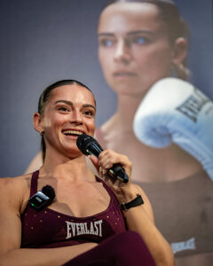 Australian boxer Skye Nicolson speaks into a microphone during an Everlast event, seated in front of a large promotional portrait backdrop.